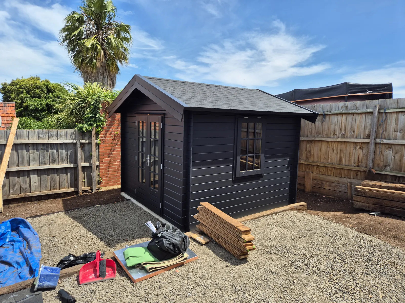 Finished black backyard cabin with French doors — clean handover