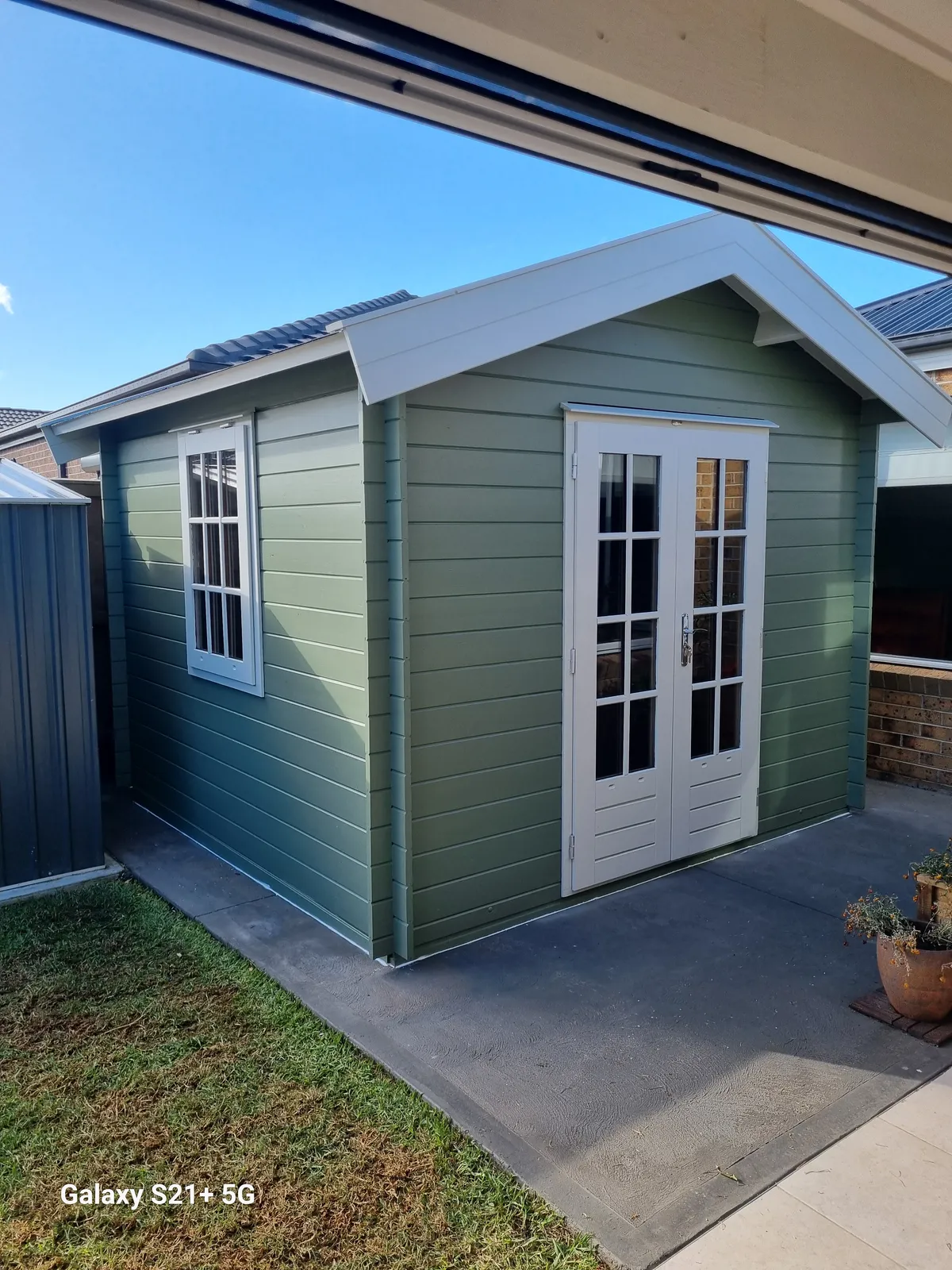 Finished sage-green cabin with white-trim French doors and gable