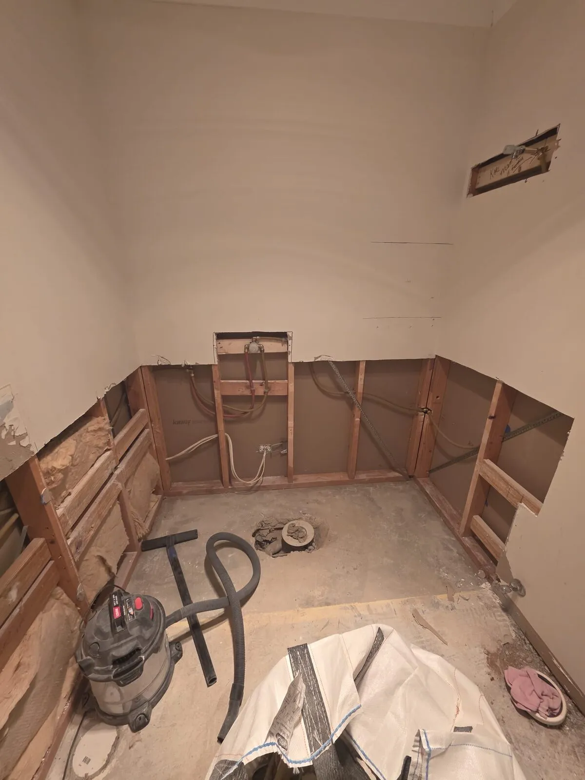 Wider strip-out view showing the full bathroom taken back to bare frame and slab